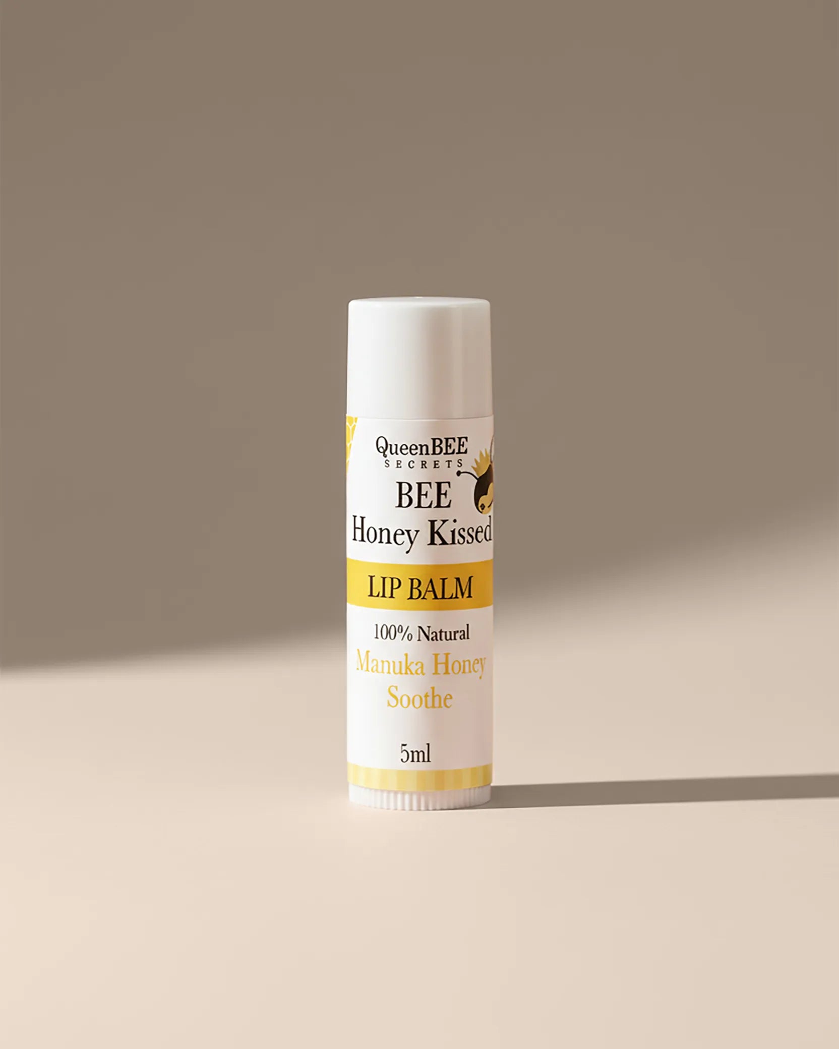 Lip balm with 'Bee Honey Kissed' branding on a beige background