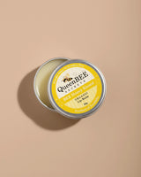 QueenBEE lip balm tin on a beige background