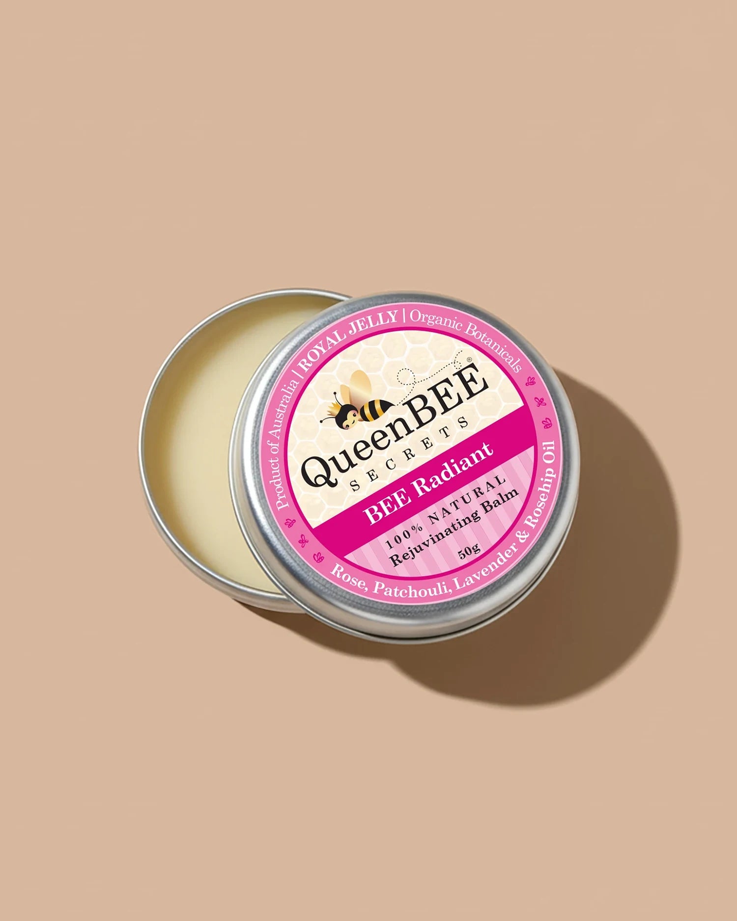 QueenBEE Radiant balm in a metal tin on a beige background