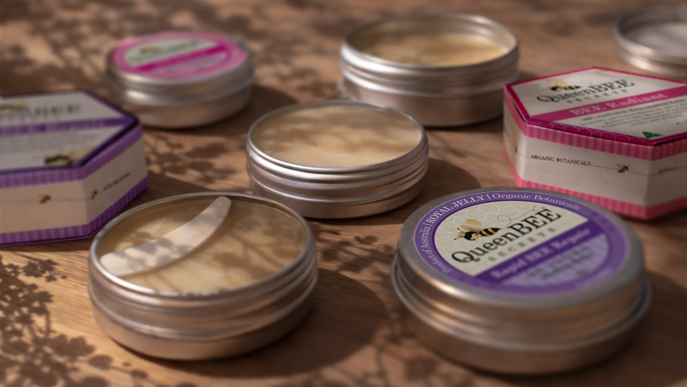 Queer Bee products including tins and boxes on a textured surface