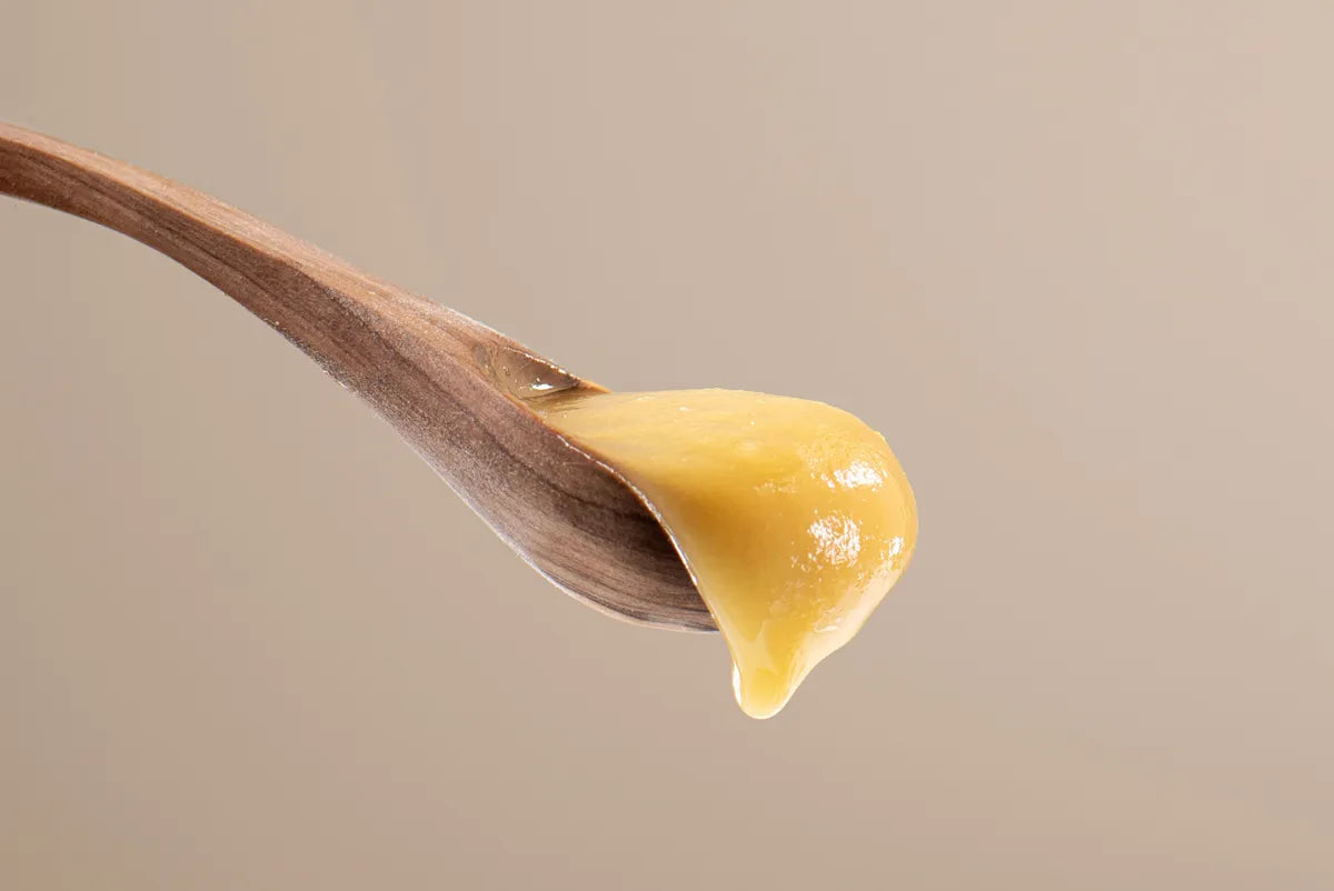 Wooden spoon with a drop of liquid balm on a beige background
