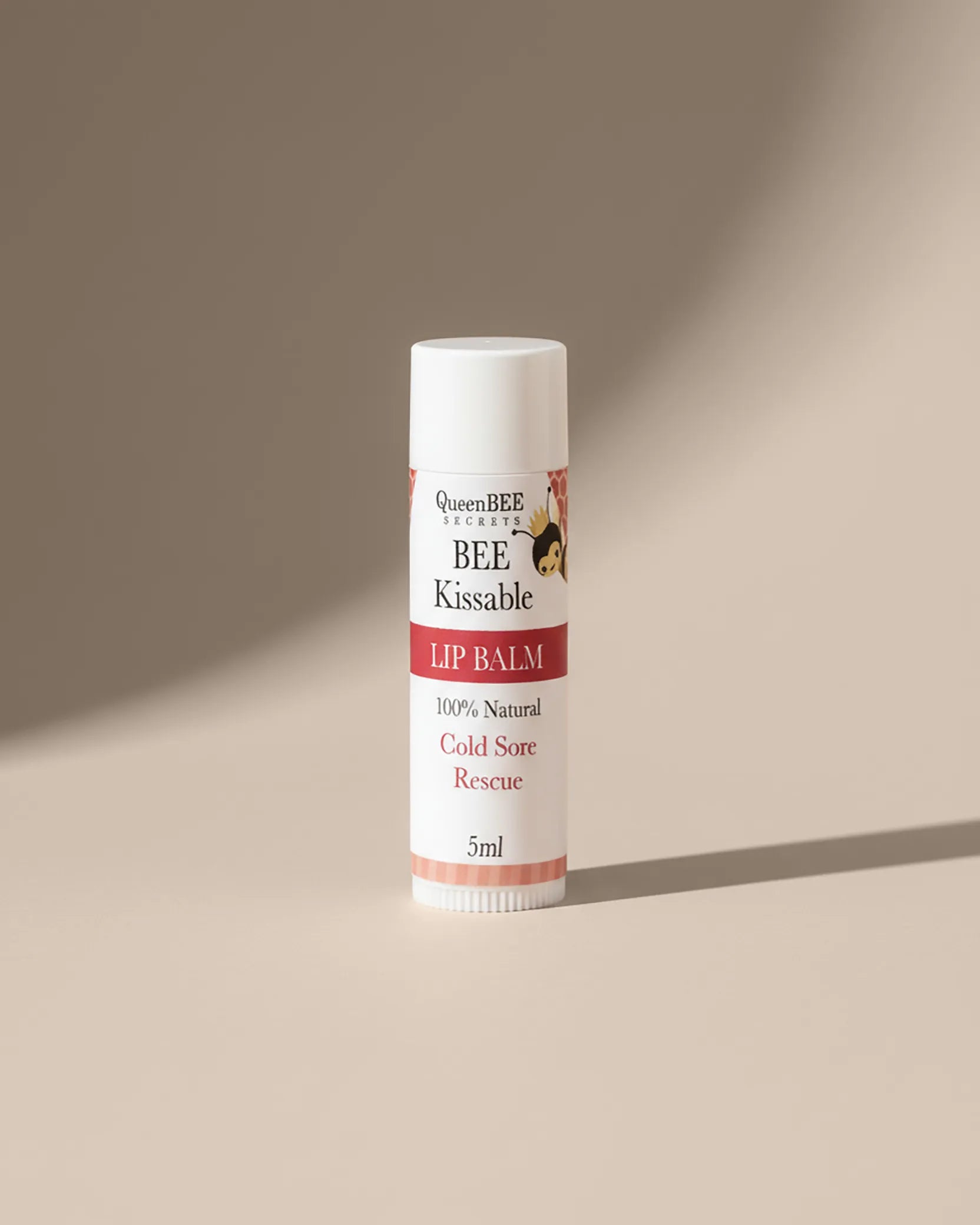Lip balm tube labeled 'BEE Kissable' on a beige background