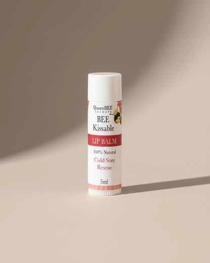 Lip balm tube labeled 'BEE Kissable' on a beige background