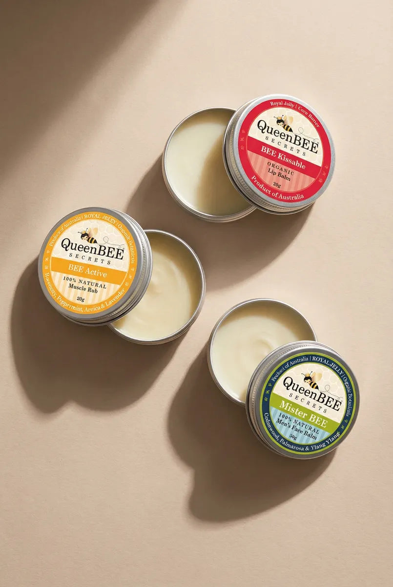 Three QueenBEE balm tins on a beige background