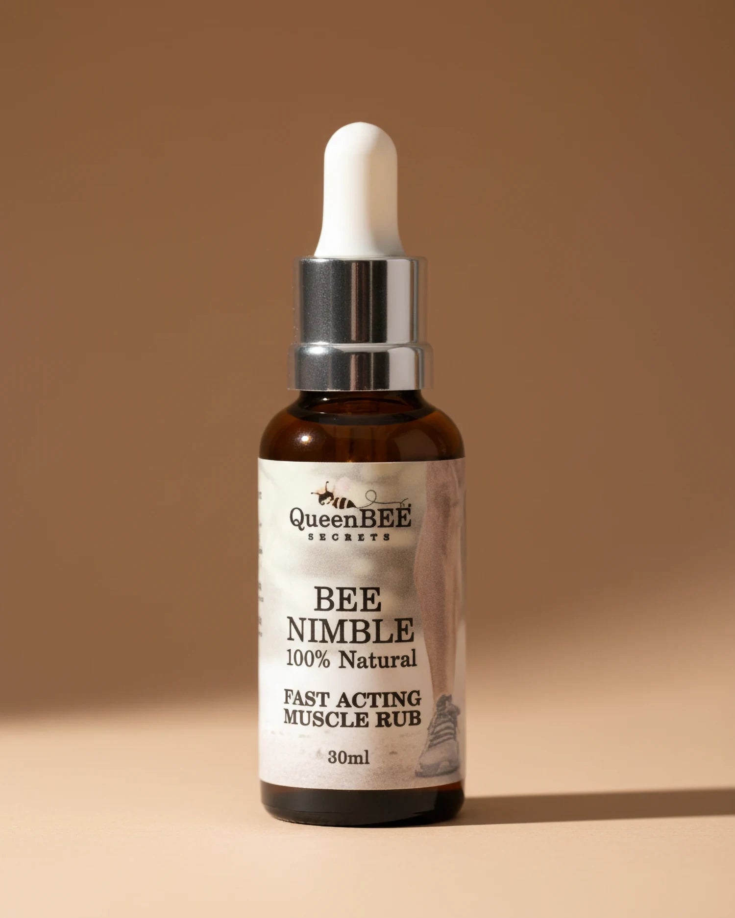 Bottle of Queen Bee Secrets Bee Nimble muscle rub on a neutral background