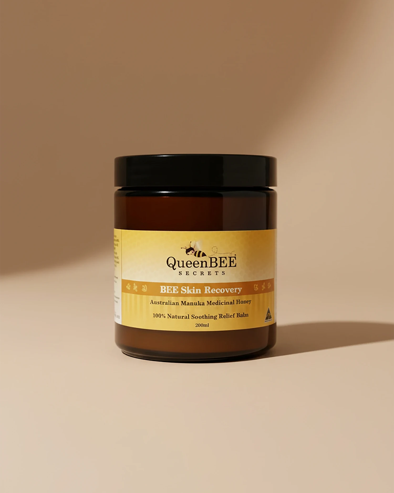 Jar of Queen Bee Skin Recovery balm on a beige background