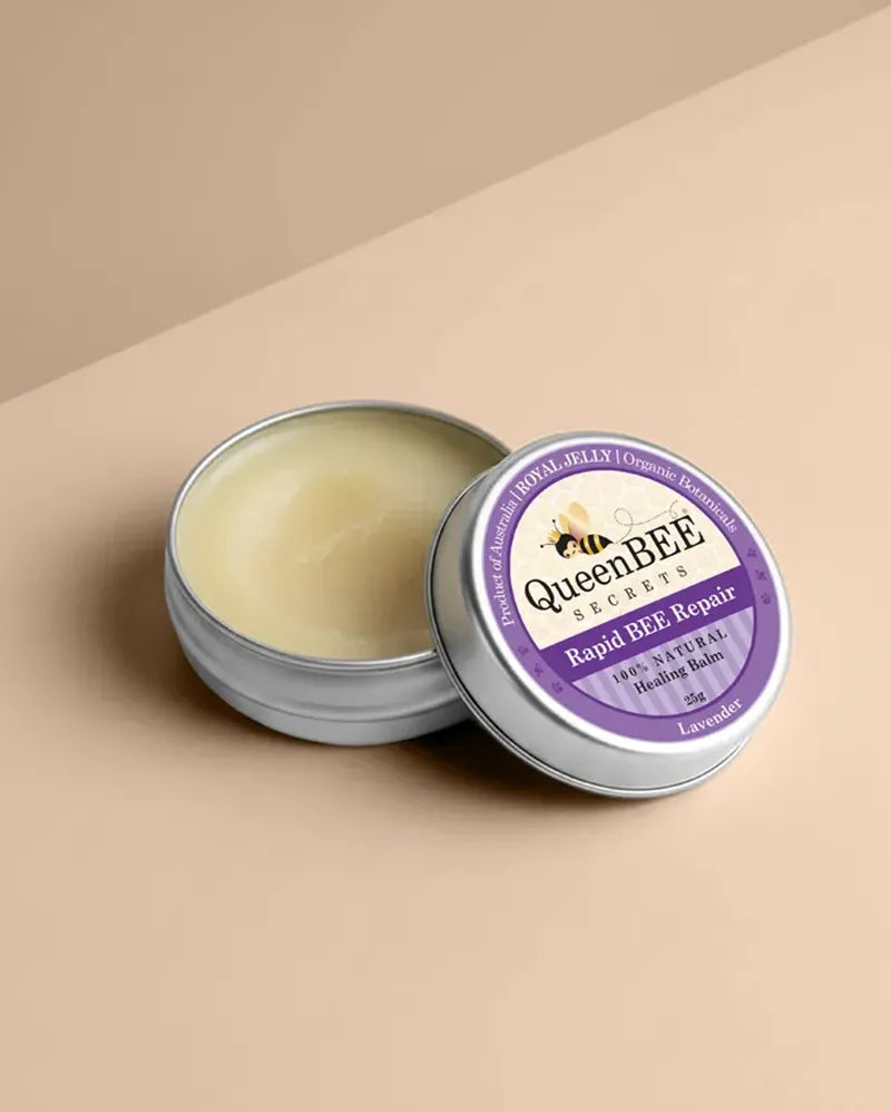 Open tin of QueenBEE Rapid BEE Repair balm on a beige background