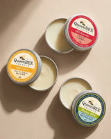 Collection of QueenBEE balms on a beige background