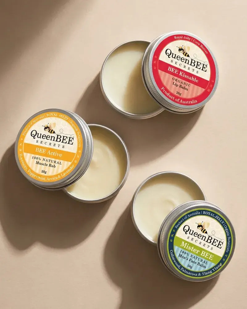 Collection of QueenBEE balms on a beige background