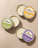 Three tins of QueenBEE products on a beige background